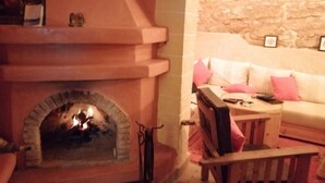 A cozy living room with a stone wall, a fireplace, and a sofa with pink cushions.
