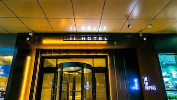 Entrada de un hotel con puerta giratoria y un letrero que dice 'HOTEL'.
