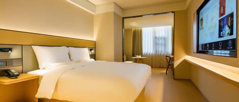 A hotel room with a large bed, bedside tables, a desk, and a television screen displaying a movie.