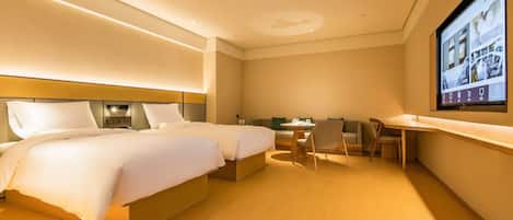 A hotel room with two beds, a desk, a chair, and a television screen.