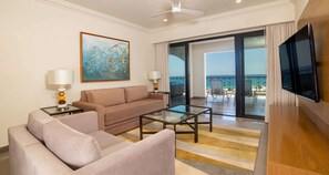 Une chambre d’hôtel avec un canapé, une table basse, une télévision, un tableau et un balcon avec vue.