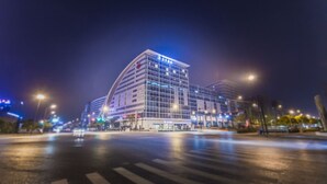 Un hotel moderno con fachada curva, varios pisos y señalización iluminada.