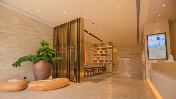 Un moderno vestíbulo de hotel con una recepción, una zona de estar y una estantería.