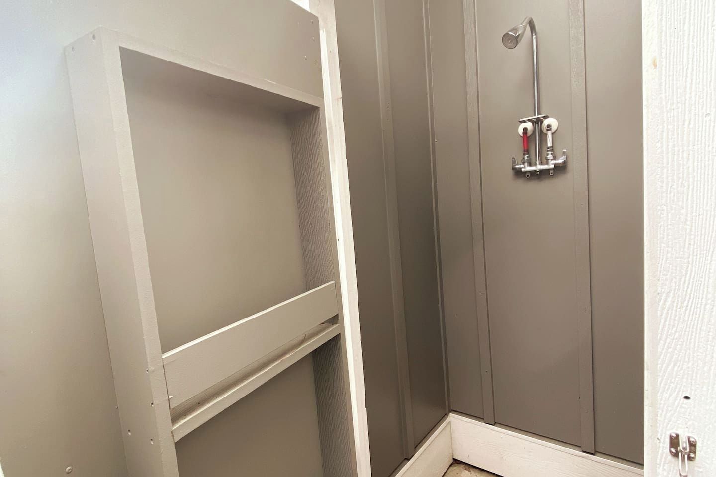 A bathroom with a shower, a white door, and a towel rack.