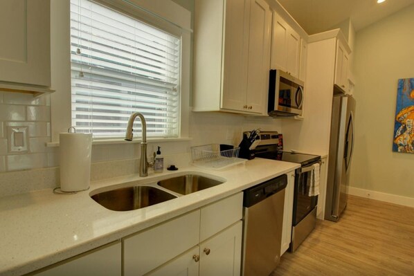 A kitchen with a double sink, stainless steel appliances, and white cabinetry.