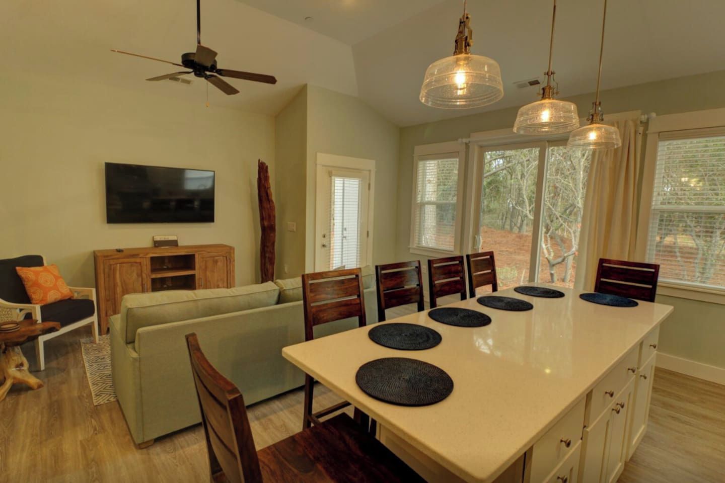A dining area with a long table, chairs, and a ceiling fan.