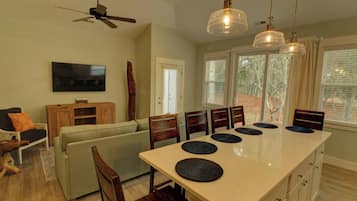 A dining area with a long table, chairs, and a ceiling fan.