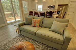 A modern living room with a sofa, a patterned rug, and a dining area with chairs.