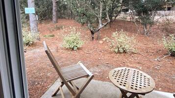 A patio area with a wooden chair and table, surrounded by trees and a sign indicating a search area.