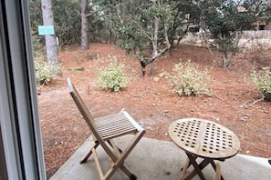 A patio area with a wooden chair and table, surrounded by trees and a sign indicating a search area.