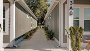 A row of single-story buildings with a central walkway, each with a small porch and a mailbox. - Dog Friendly Luxury Condo, Walk to the Beach (Corolla)
