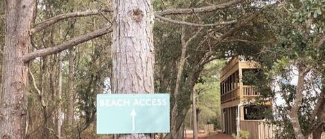 A sign indicating beach access with a directional arrow.