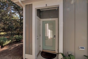 A building entrance with a green door, a mailbox, and a small porch area.