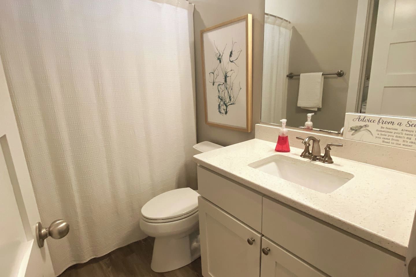 Un baño con inodoro, lavamanos, espejo y cortina de ducha.