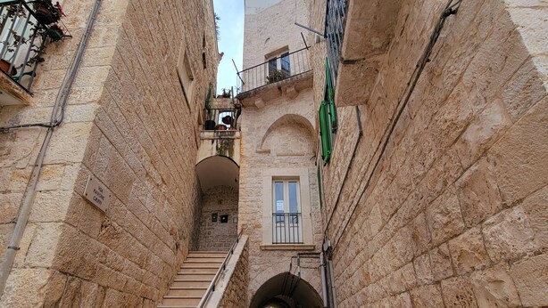 Uma escadaria de pedra estreita leva a um arco numa construção histórica.