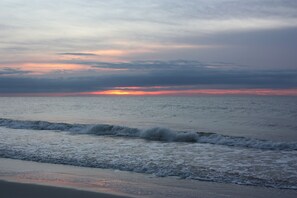 A beach with waves and a sunset.