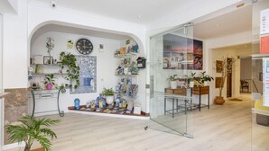 Un interior moderno con una recepción, un reloj y diversas plantas.