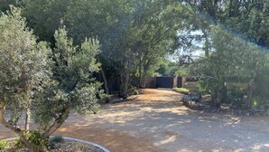 A gravel driveway leading to a gated entrance surrounded by trees and shrubs. - Holiday home - 1-6 person(s) - quiet location - large fenced property (Méjannes-le-Clap)