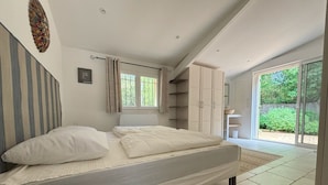 A bedroom with a bed, a window, a wardrobe, and a bathroom visible through a sliding door. - Holiday home - 1-6 person(s) - quiet location - large fenced property (Méjannes-le-Clap)
