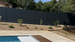 A swimming pool with clear blue water, surrounded by a wooden deck and a tiled patio area. - Holiday home - 1-6 person(s) - quiet location - large fenced property (Méjannes-le-Clap)