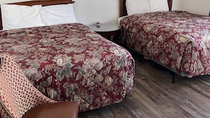 A hotel room with two beds, a wooden headboard, a small round table with a clock, and a framed picture on the wall. - CRYSTAL MOTEL (Red Bluff)