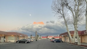 A parking lot with cars, a building with a red roof, and a tree. - CRYSTAL MOTEL (Red Bluff)