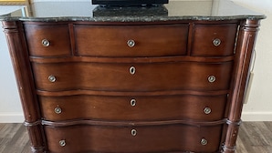 A wooden dresser with a microwave on top, drawers with knobs, and a mirror on the left. - CRYSTAL MOTEL (Red Bluff)