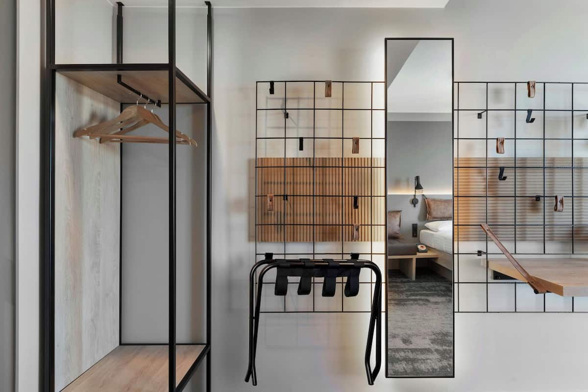 Une chambre à coucher moderne au design minimaliste, comprenant un lit, une table de chevet et un meuble de rangement mural doté de crochets.