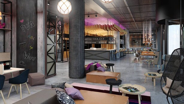 Um café espaçoso com móveis modernos, um pilar grande e luminárias pendentes.