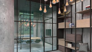 Um interior moderno com divisória de vidro, prateleiras de madeira e luminárias pendentes.