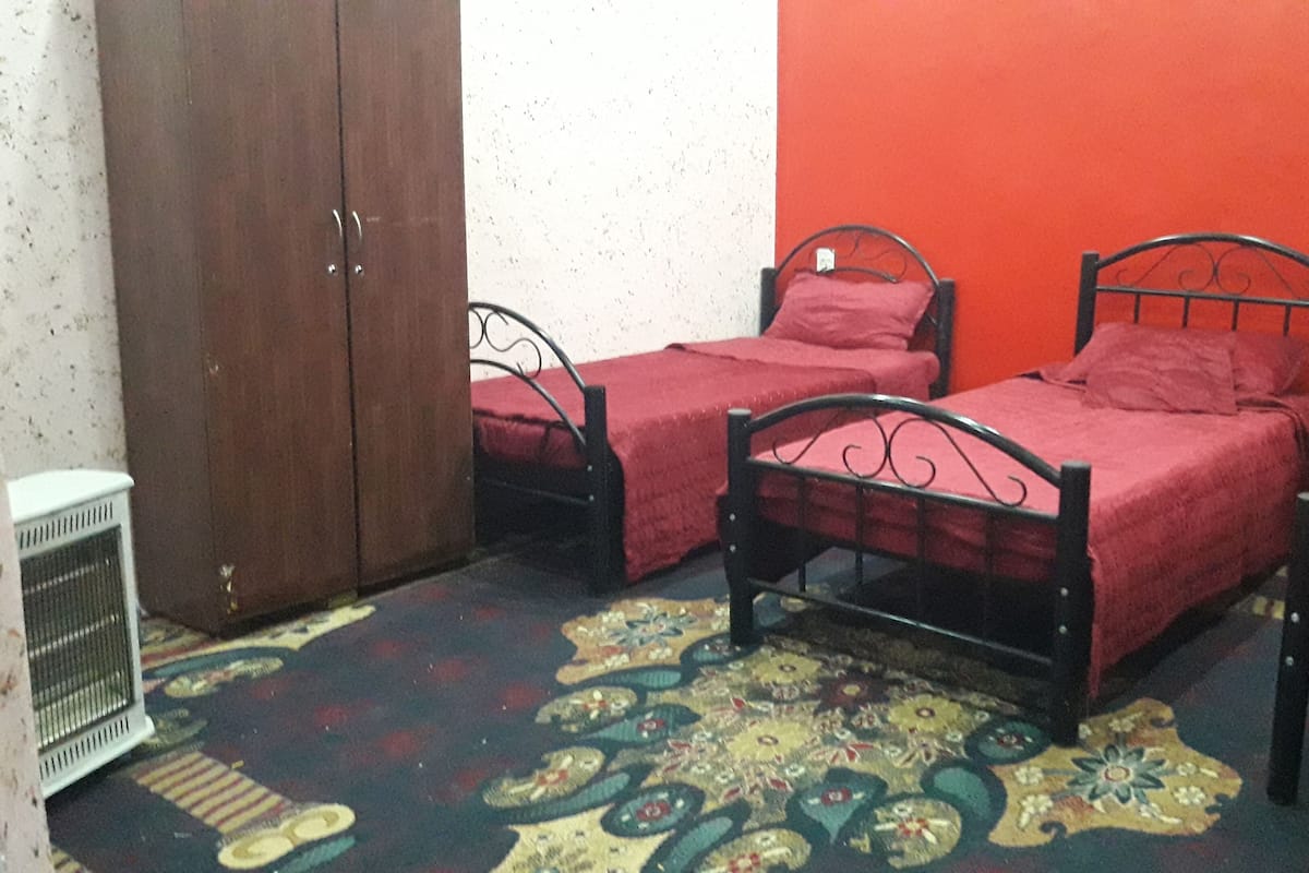 A small, compact room with three single beds, a wardrobe, and a radiator.