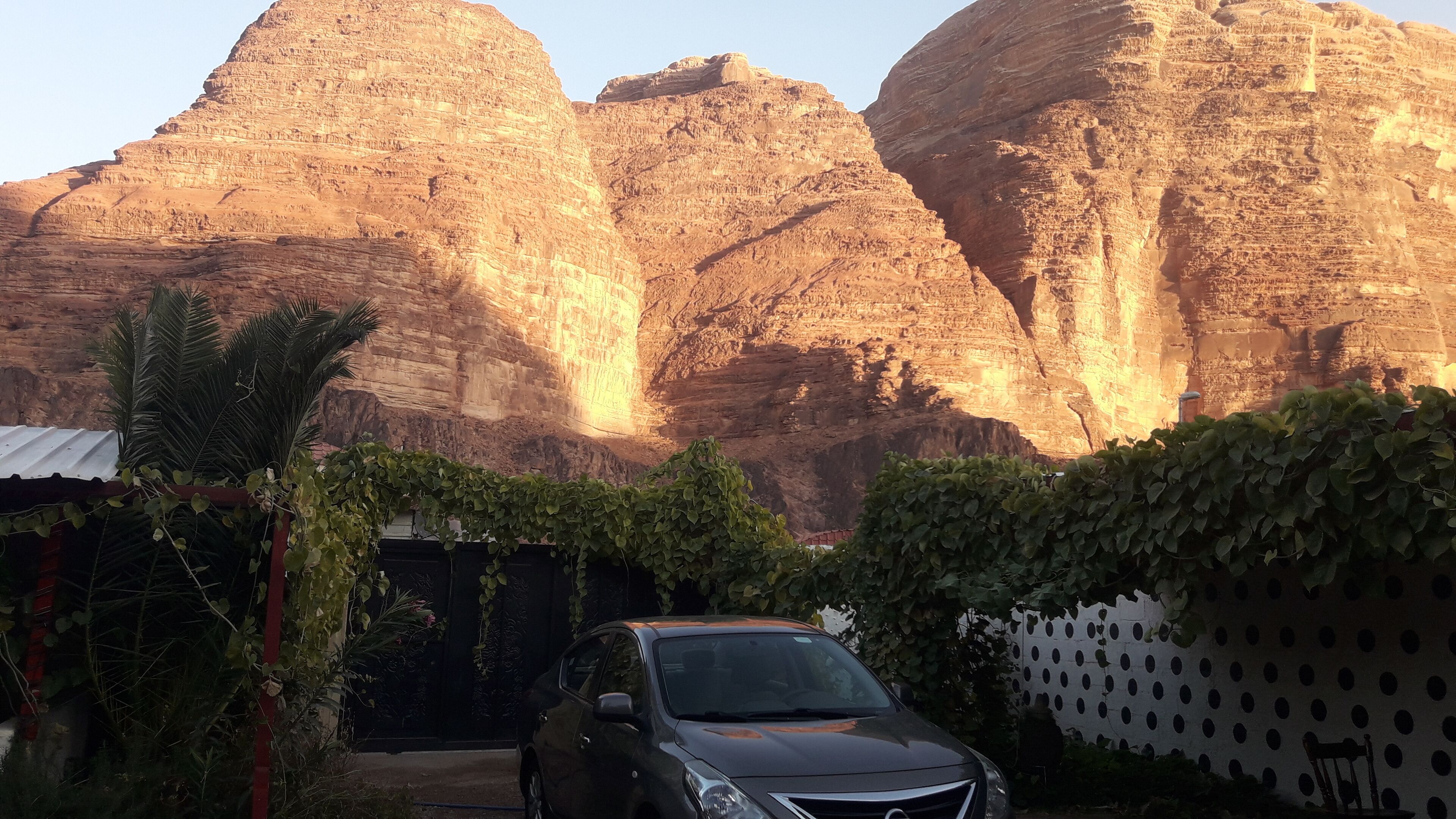 Un coche aparcado frente a un edificio con vistas a grandes formaciones rocosas.