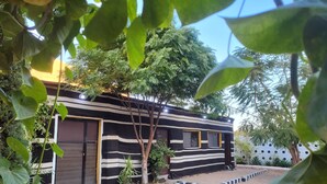 Un edificio moderno con fachada a rayas negras y blancas, un pequeño jardín delantero y un camino de entrada de grava.