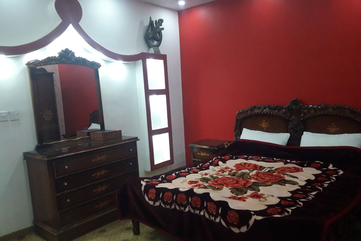 A bedroom with a bed, dresser, and a mirror.