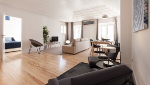 A spacious living area with a sofa, dining table, and chairs. A television is on a stand, and a plant is in the corner. - Santa Justa Apartments, Downtown Center (Lisbon)