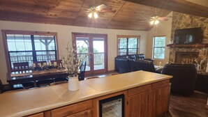 A spacious kitchen with wooden cabinets, a central island, and a built-in refrigerator. There are large windows providing natural light and a stone fireplace. - Frio Honeymoon - Best view in Concan (Concan)