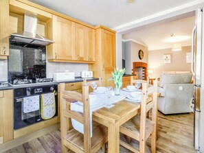 A modern kitchen with wooden cabinets, a dining table set for four, and a built-in oven.