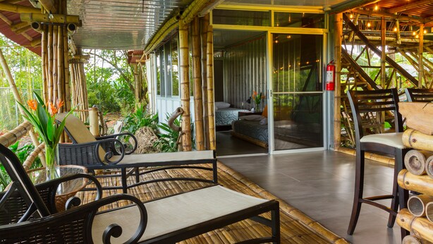 A bamboo-themed room with a glass door leading to a balcony, wicker furniture, and a fire extinguisher. - Bamboo Beach House Steps away from secluded beach (Provincia de Puntarenas)