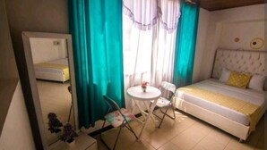 A small room with a bed, a table, and two chairs.