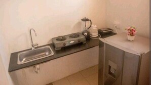 A compact kitchen with a sink, stove, and small refrigerator.