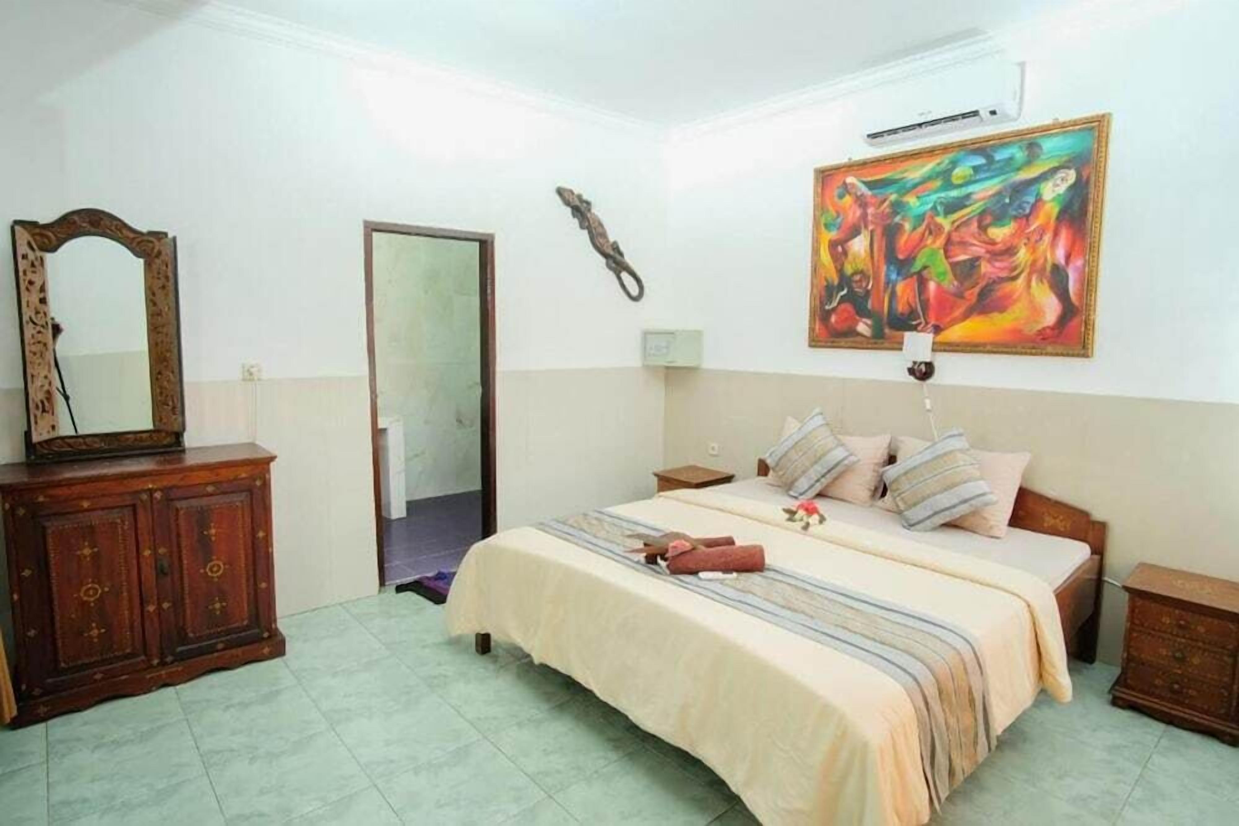 Une chambre à coucher avec un lit, une commode, un miroir, un tableau et une porte.