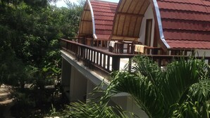 Un edificio de estilo bungalow con techo de tejas rojas y un balcón.
