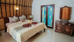 Un dormitorio con cama, almohadas, cómoda, espejo y puerta con cortinas coloridas.