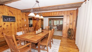 Un comedor de madera con una mesa grande, sillas y un letrero que dice 'Welcome'.