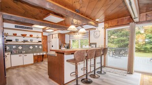 Una cocina con armarios de madera, una barra con taburetes y vistas al exterior.
