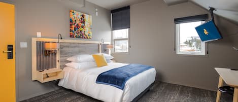 Un dormitorio moderno con una cama, un escritorio, una ventana y un cuadro en la pared.