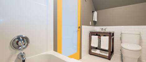 Een badkamer met een bad, toilet en een klein wastafeltje met spiegel.