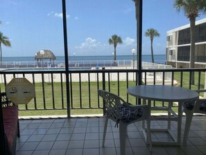 Un balcon donnant sur la plage, une table et des chaises, et un panneau indiquant « Il est interdit de fumer ».