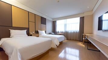 A hotel room with two beds, a desk, a TV, and a large window with curtains.