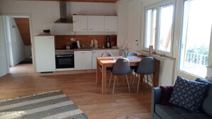 Une cuisine moderne avec des meubles blancs, une table à manger en bois et un four encastré.